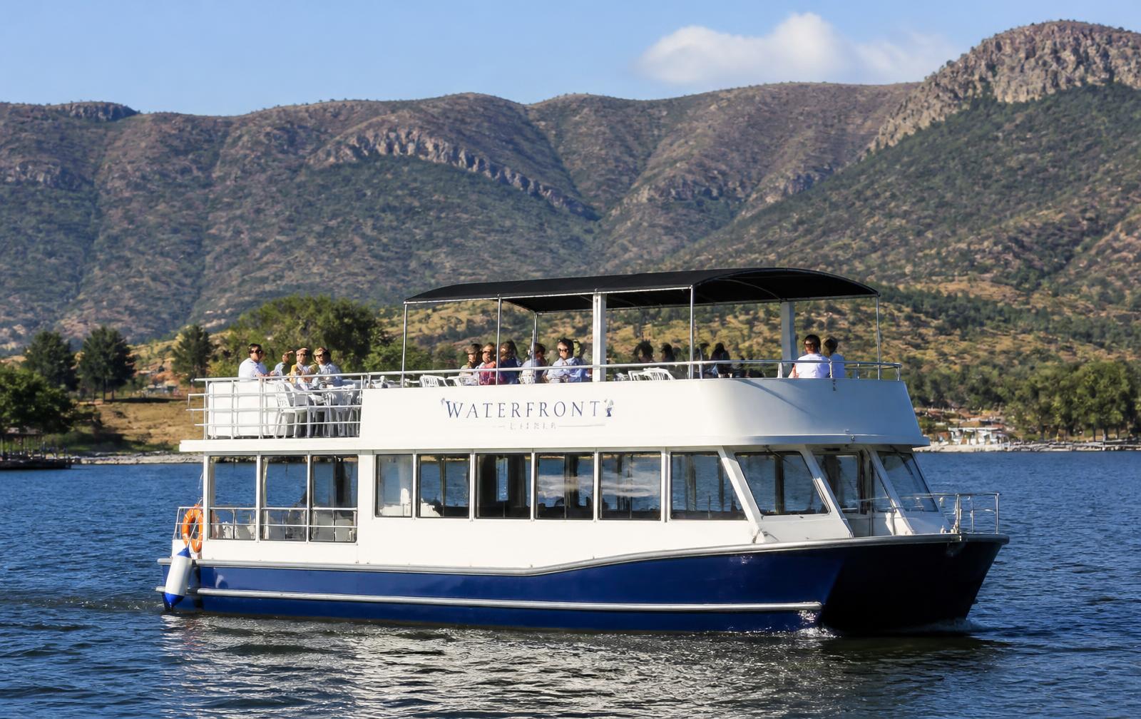 Leisure cruise boat on Hartbeespoort Dam with the Magaliesberg at sunset